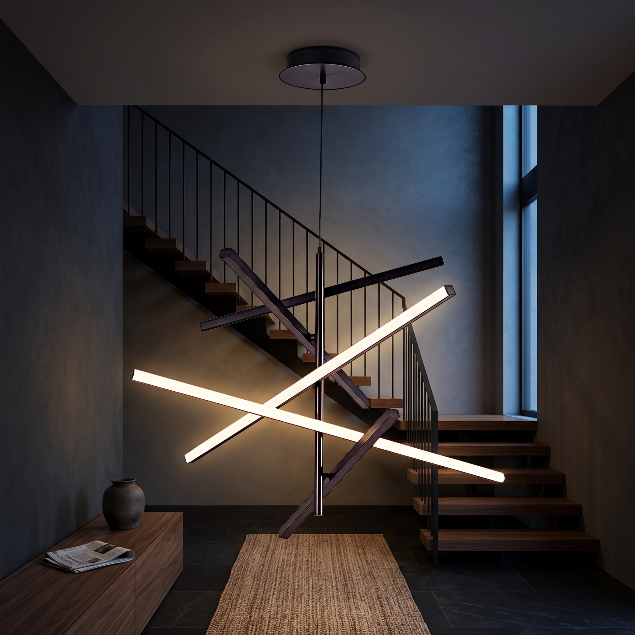 Nikandros Nordic linear chandelier in matte black lit in a dark charcoal double-height entrance hall with walnut staircase