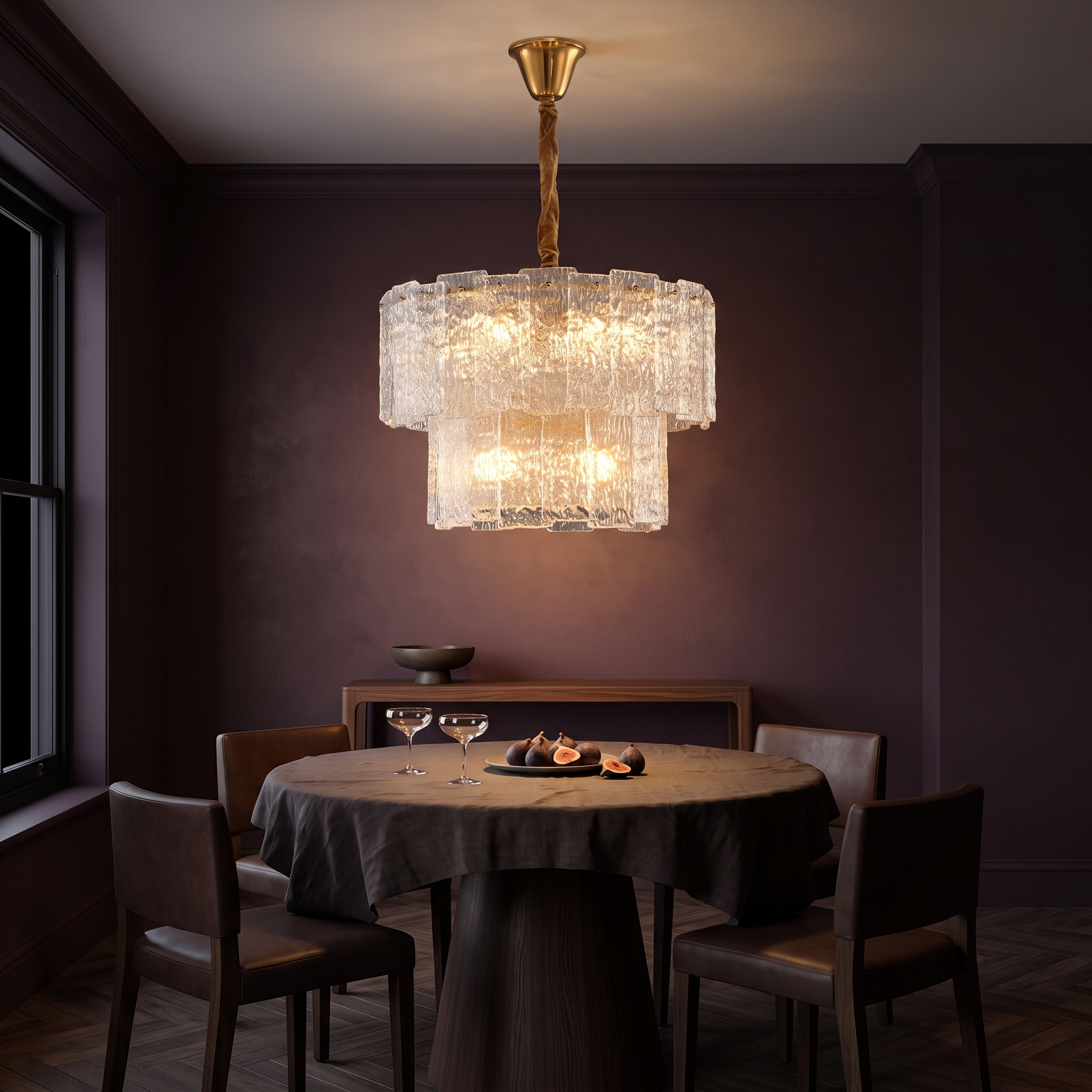 Eirene brass and textured glass tiered chandelier lit over a round table in a dark aubergine dining room at night