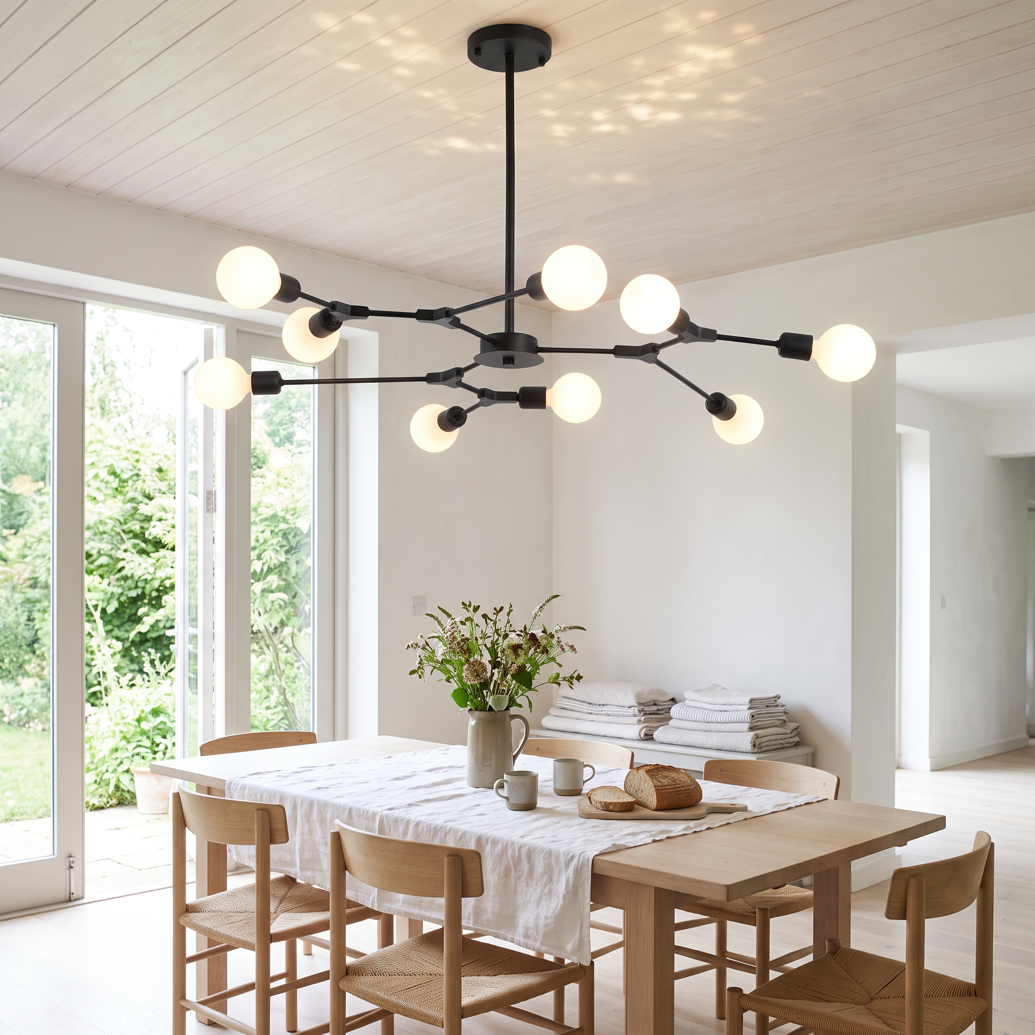 Berenika nine-light sputnik chandelier in black lit over an oak table in a bright white garden-room breakfast space