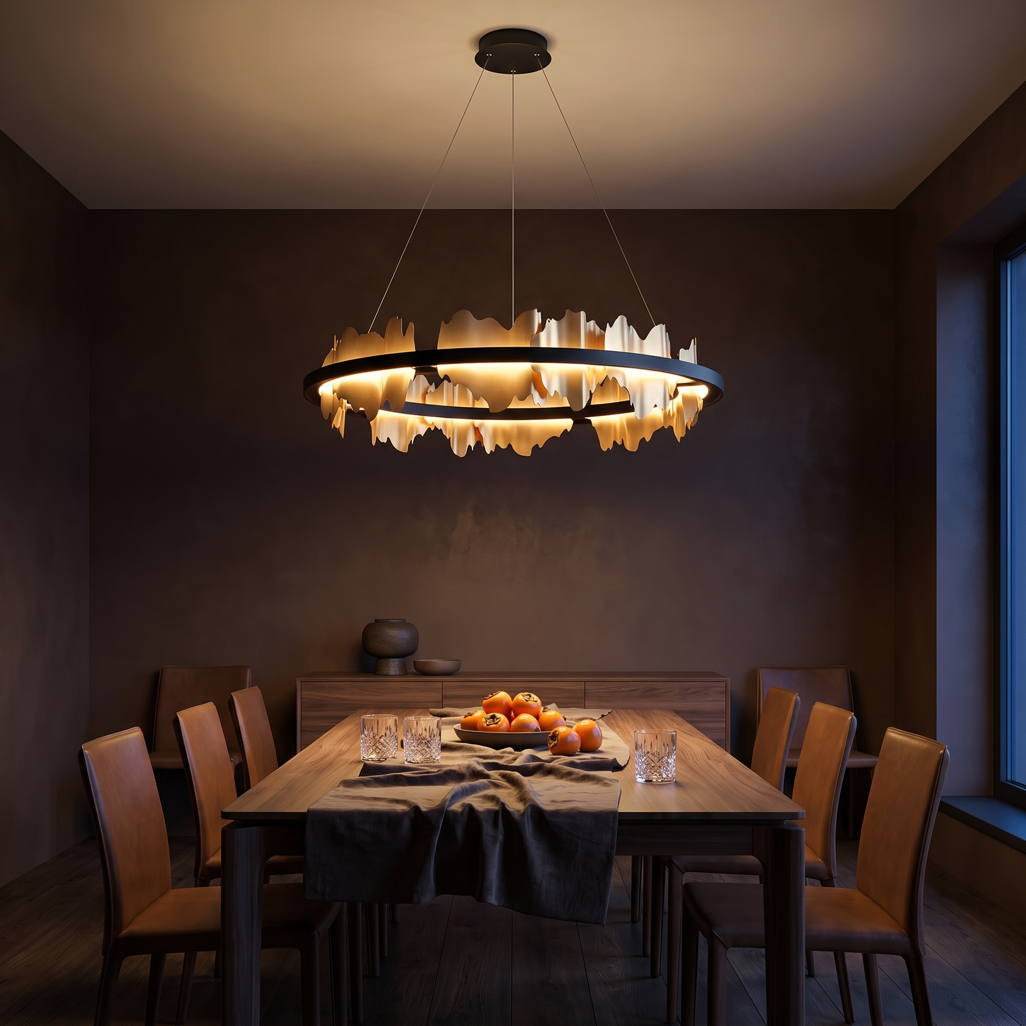 Danae metal leaf round chandelier in black and gold lit over a walnut dining table in a dark chocolate plaster dining room