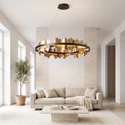Danae metal leaf round chandelier in black and gold lit in a bright travertine and oak living room