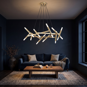 Elpis 20-light sputnik chandelier in gold lit over a walnut coffee table in a dark ink blue lounge at night
