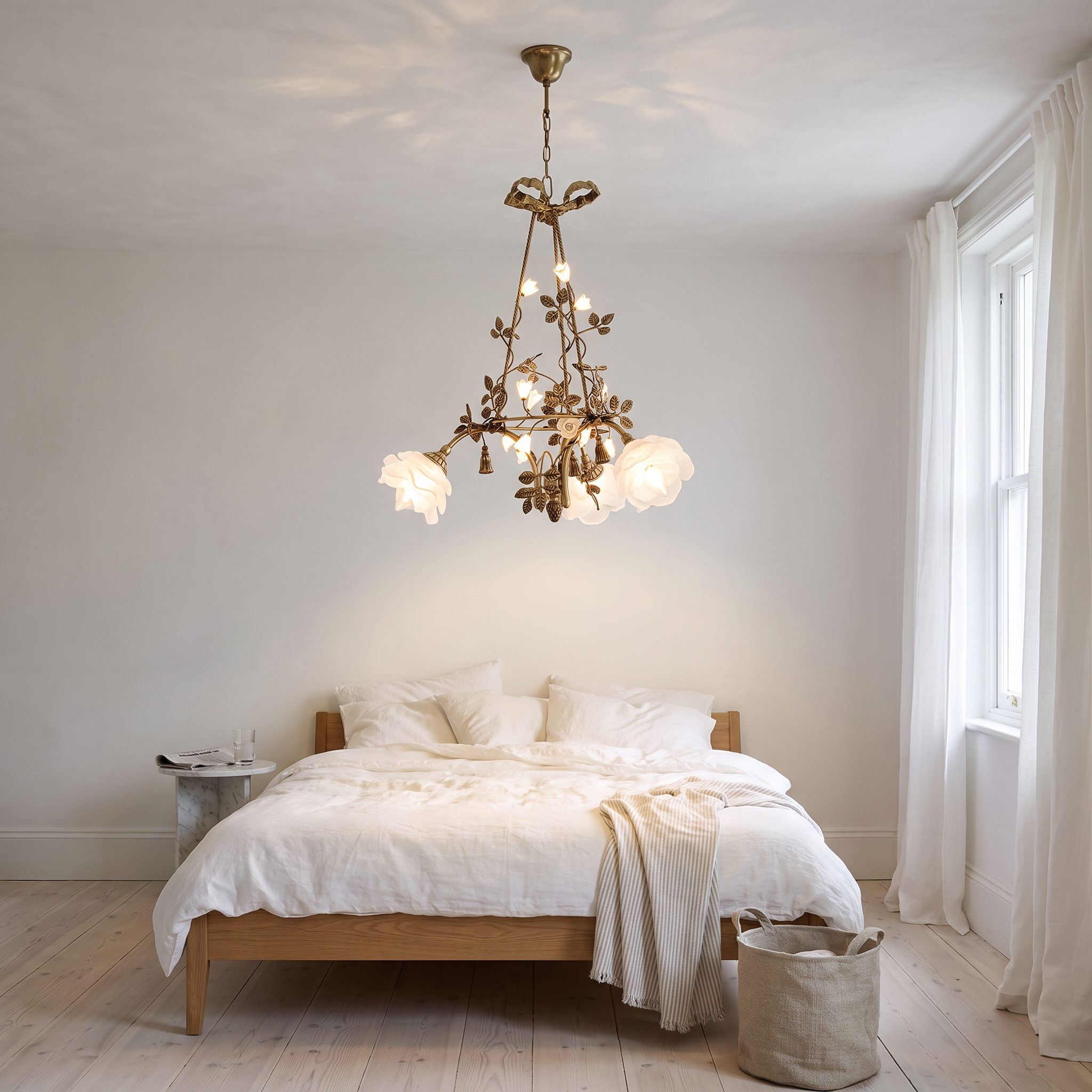Erato brass and glass flower chandelier lit in a bright white plaster and oak bedroom with linen bedding