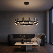 Diokles black ring chandelier with smoked glass cylinders lit in a dark concrete living room with travertine table