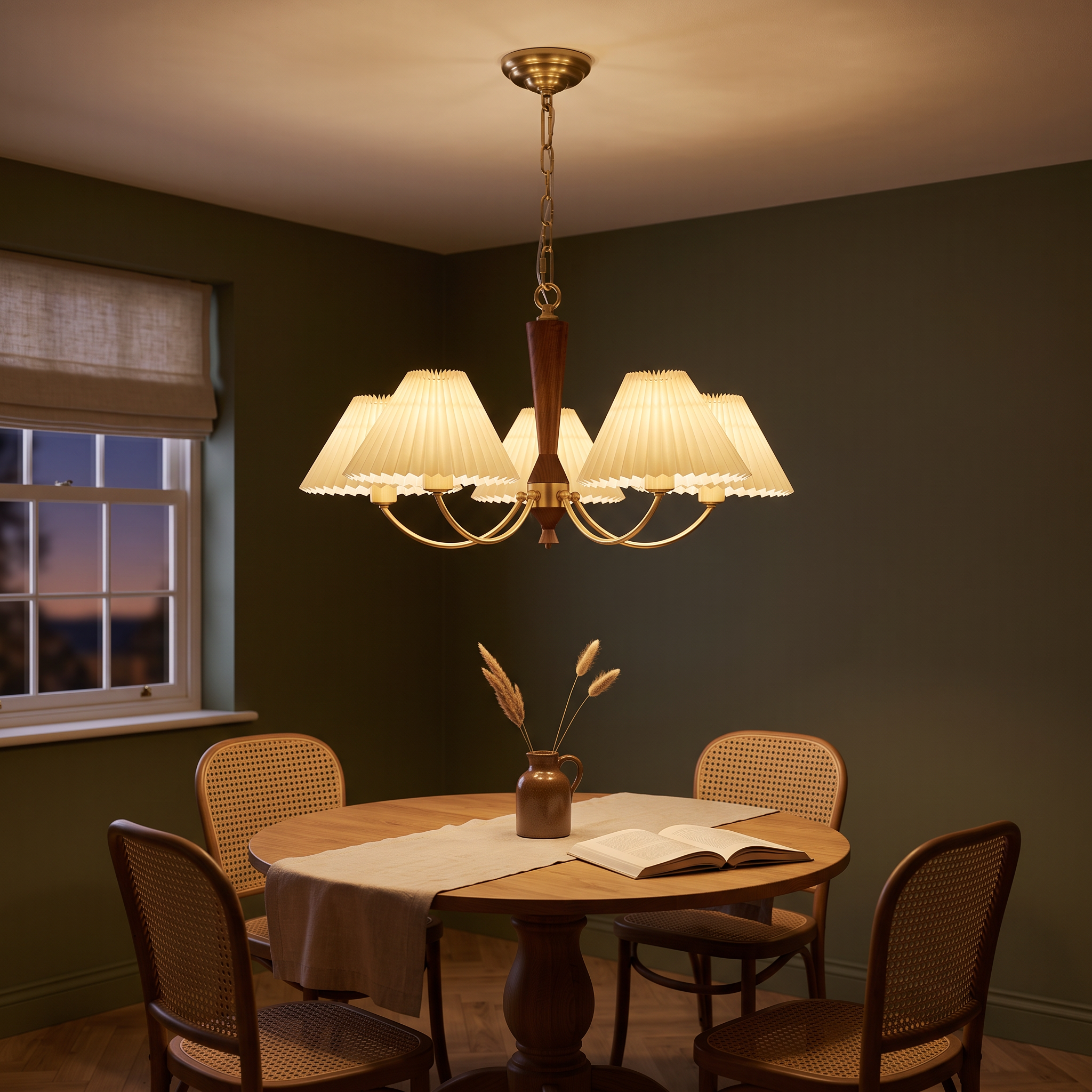 Baukis five-light brass and walnut chandelier with cream pleated shades lit over an oak table in an olive-green dining nook