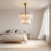 Eirene two-tier brass and ice-glass chandelier in a bright oak and linen bedroom