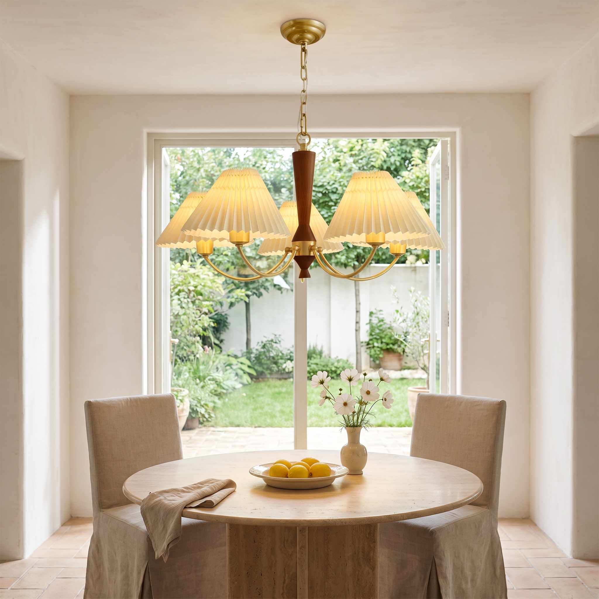 Baukis five-light brass and walnut pleated-shade chandelier above a travertine table in a bright garden room