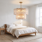 Eirene Brass and Glass Tiered Chandelier in a bright white bedroom with oak bed and linen bedding