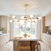 Berenika Nine-Light Sputnik Metal Chandelier in brass over a marble island in a bright white oak kitchen