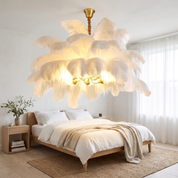 Ariston Brass and Feather Chandelier in white above an oak bed in a bright sunlit bedroom