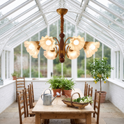 Demophon lily flower glass chandelier lit above a pine table in a bright Victorian glasshouse garden room