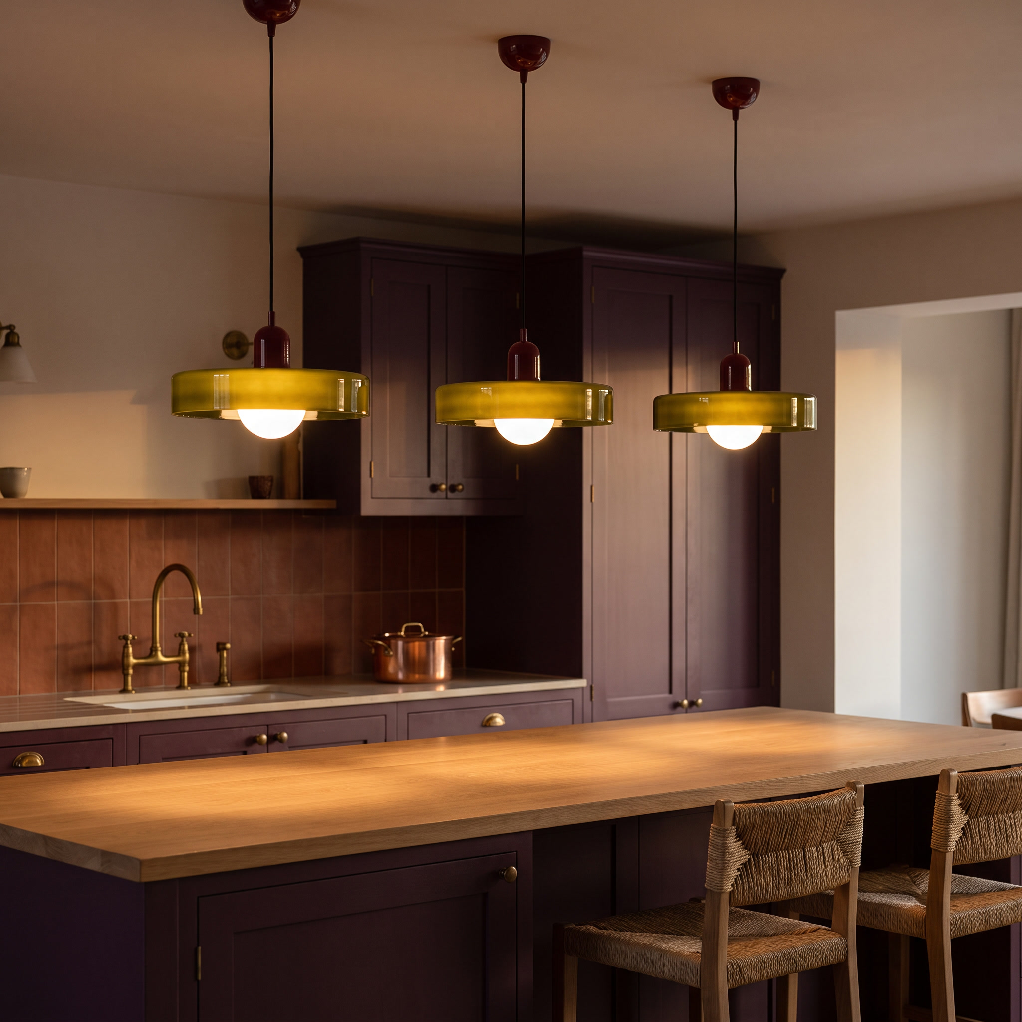 Three Iolaos colored glass pendant lights in a row over a plum and oak kitchen island