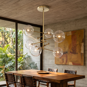 Hegesias brass globe glass chandelier lit over a rosewood table in a concrete-walled modernist dining room