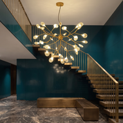 Gorgias 36-light cluster chandelier in gold in a double-height stairwell