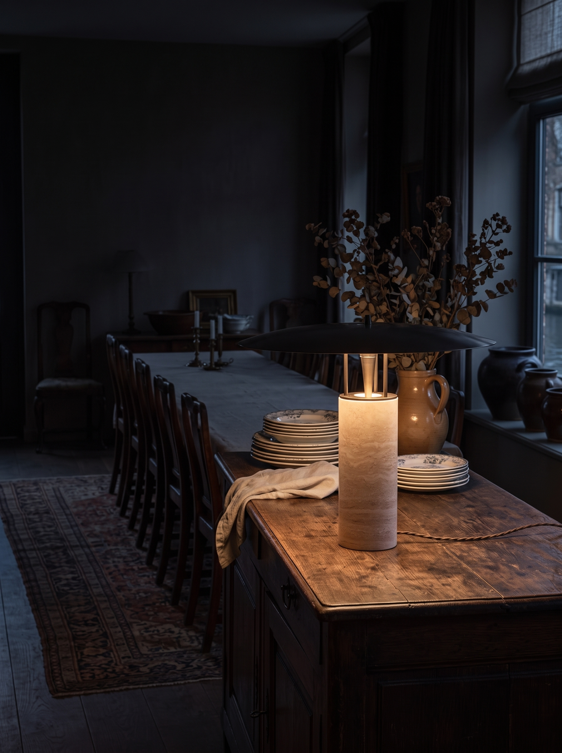 Melaina travertine and metal table lamp at night in a furnished dining room