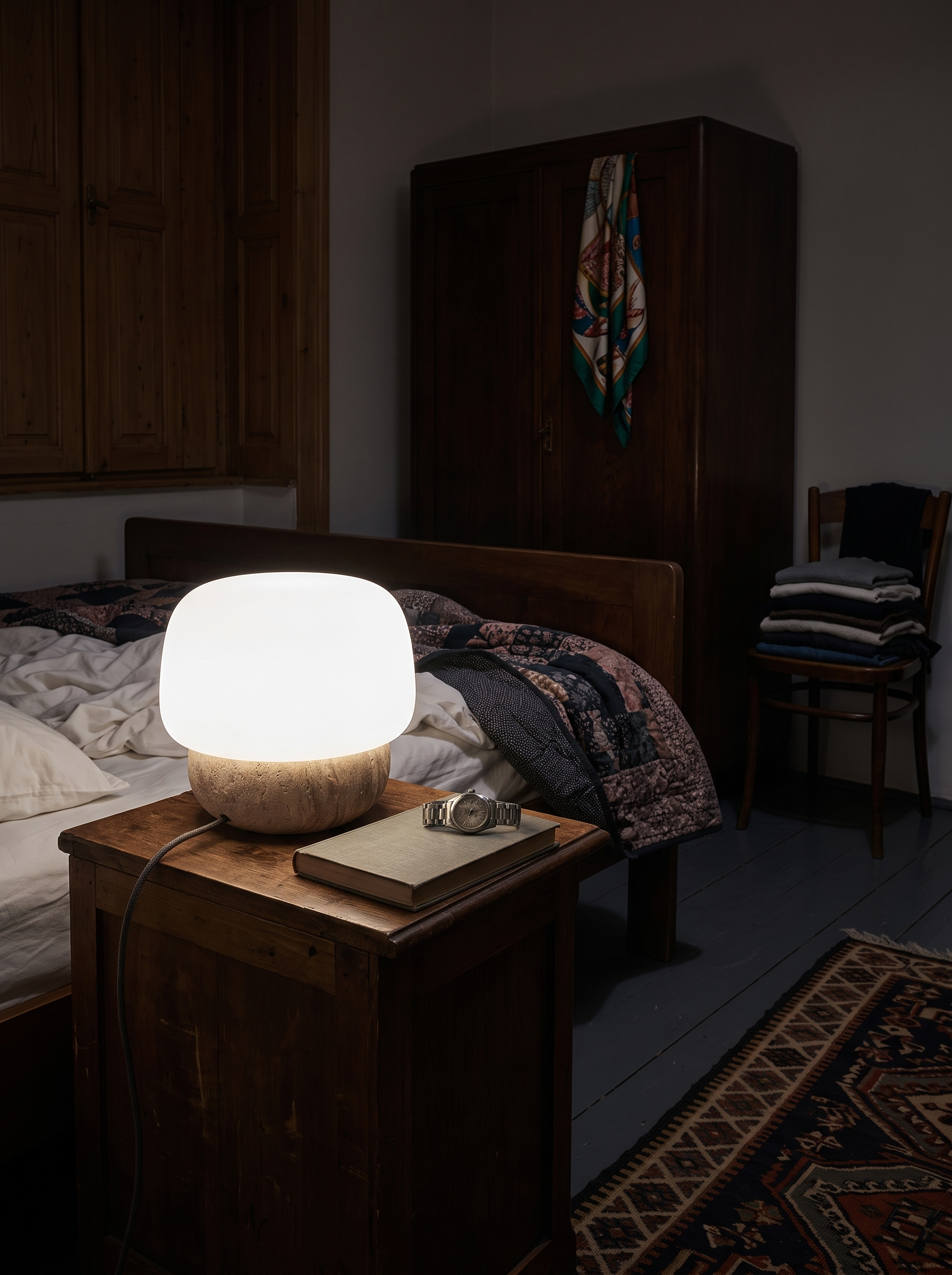 Pasithea travertine and glass table lamp at night in a furnished bedroom