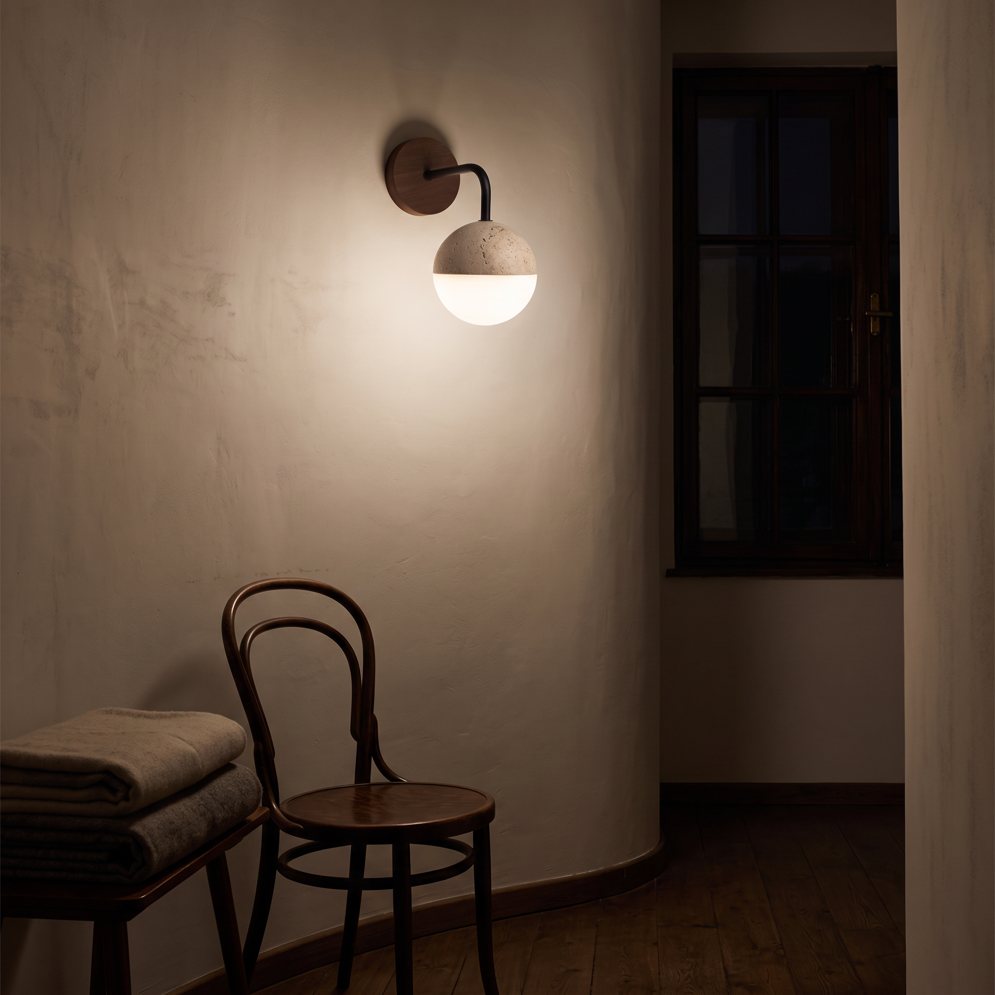 Kirke Travertine and Polycarbonate Orb Sconce lit at night on a Bucharest interwar villa landing