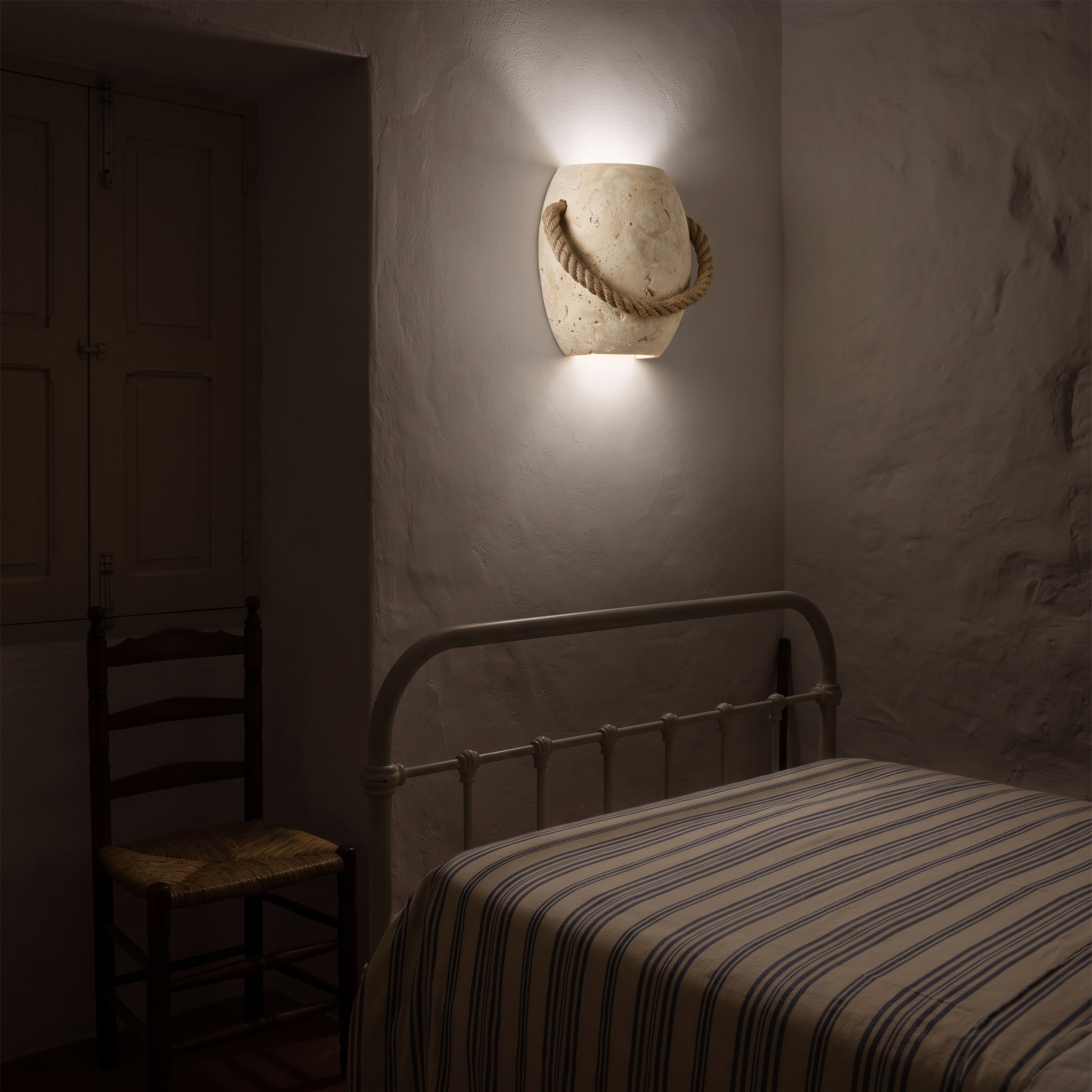 Nereus Travertine and Hemp Rope Wall Sconce lit at night in a Nazare fisherman's cottage bedroom