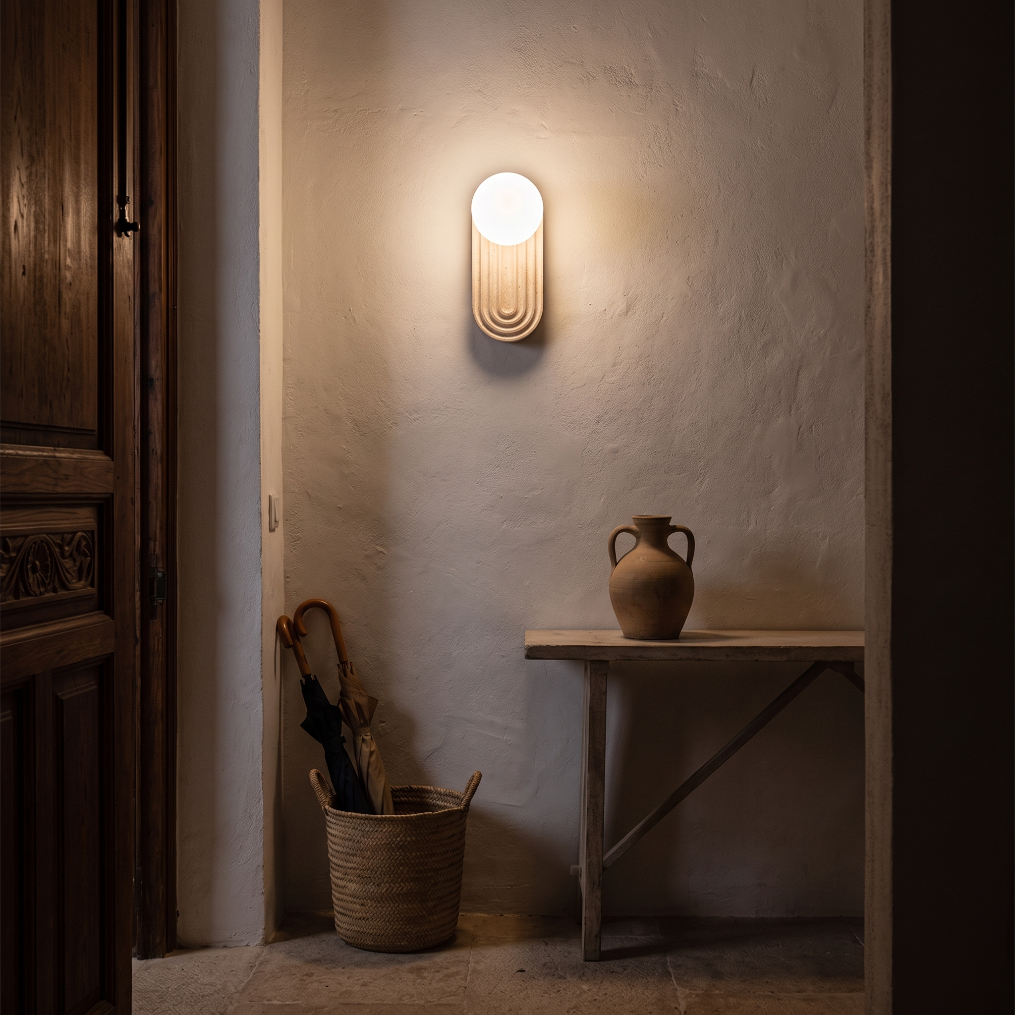 Nesaia Grooved Travertine Wall Light lit at night in a Palma de Mallorca townhouse entrance hall