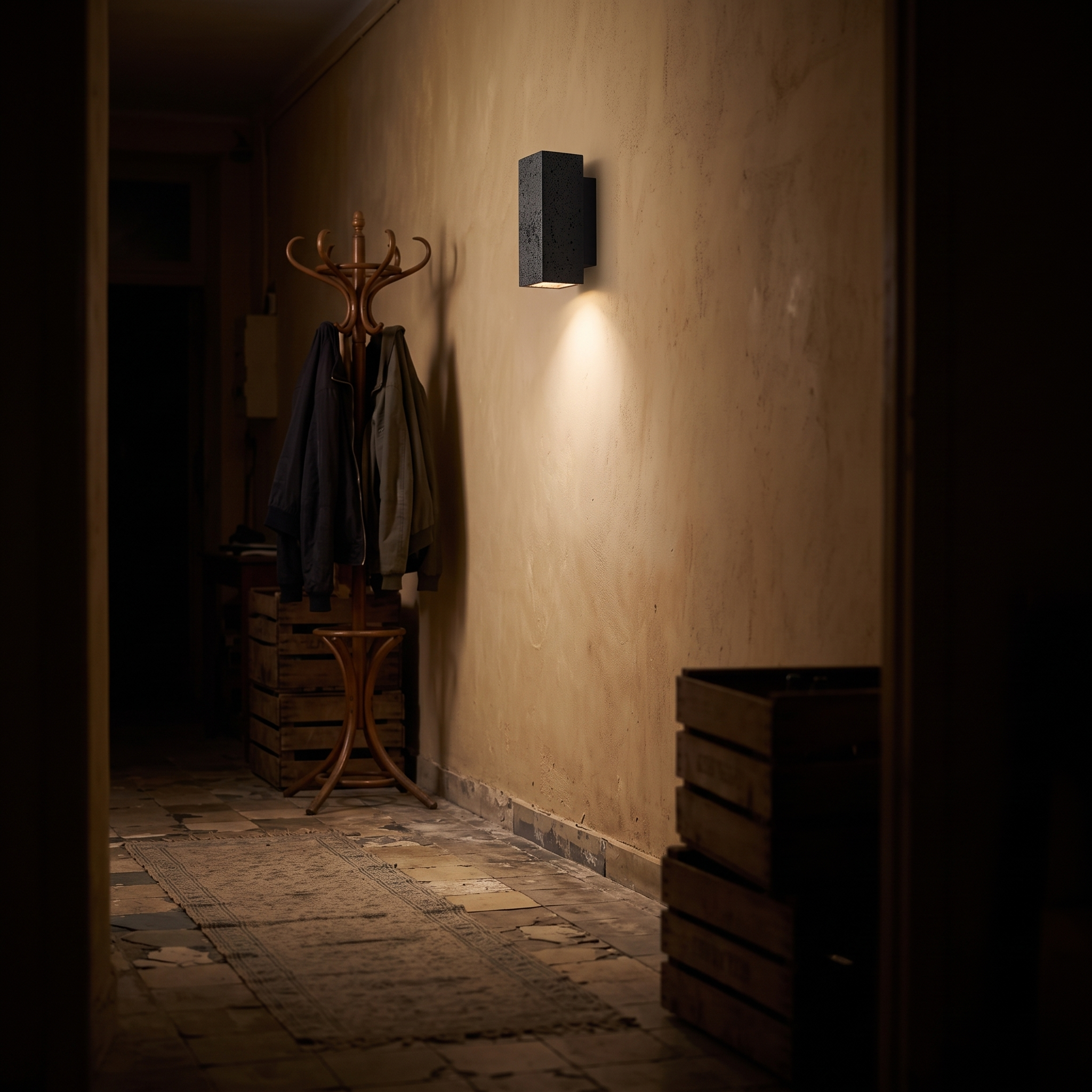 Ophion Black Travertine Block Wall Lamp lit at night in a Marseille Panier apartment hallway