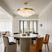 Hermione brass and glass rod chandelier installed over a contemporary dining table